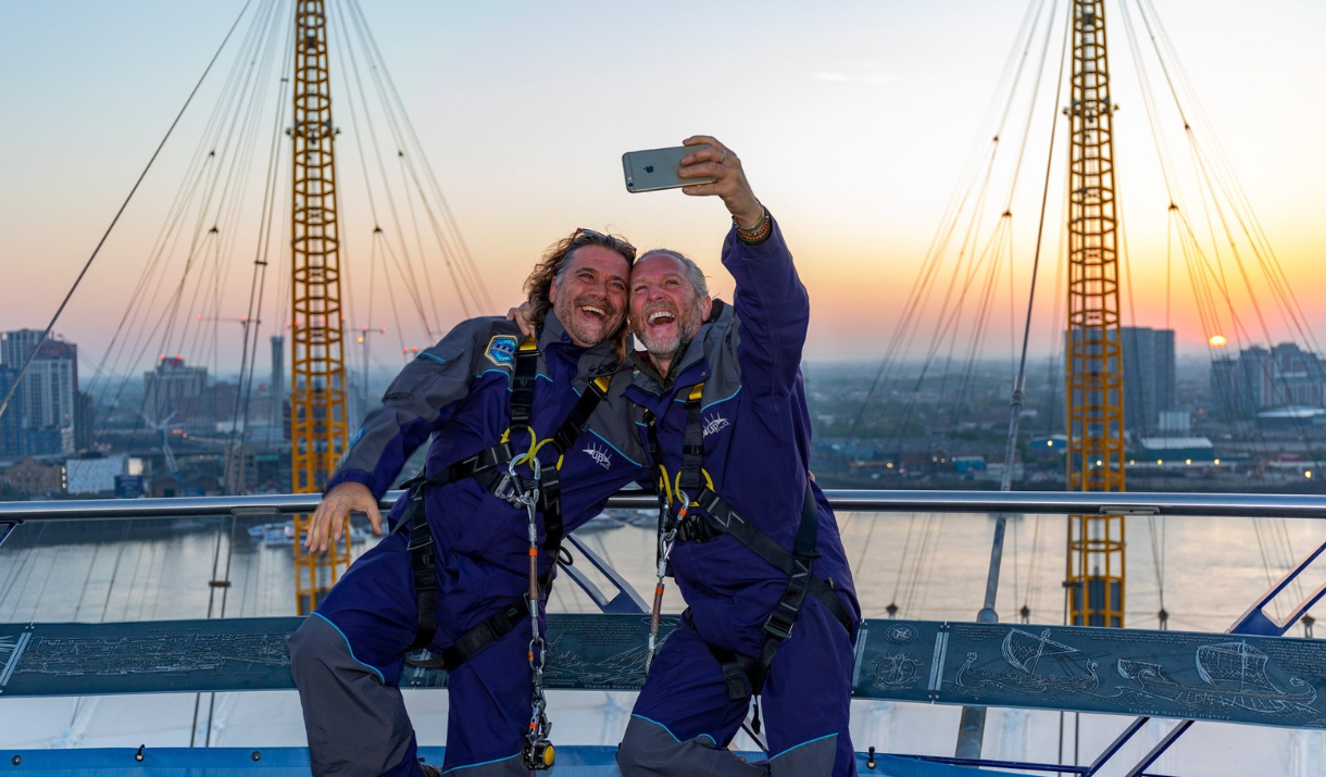 Two men enjoy a selfie at Up at The O2 at sunset on Greenwich Peninsula